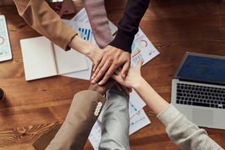 An overhead view of a table with a group of peoples hands on top of each others
